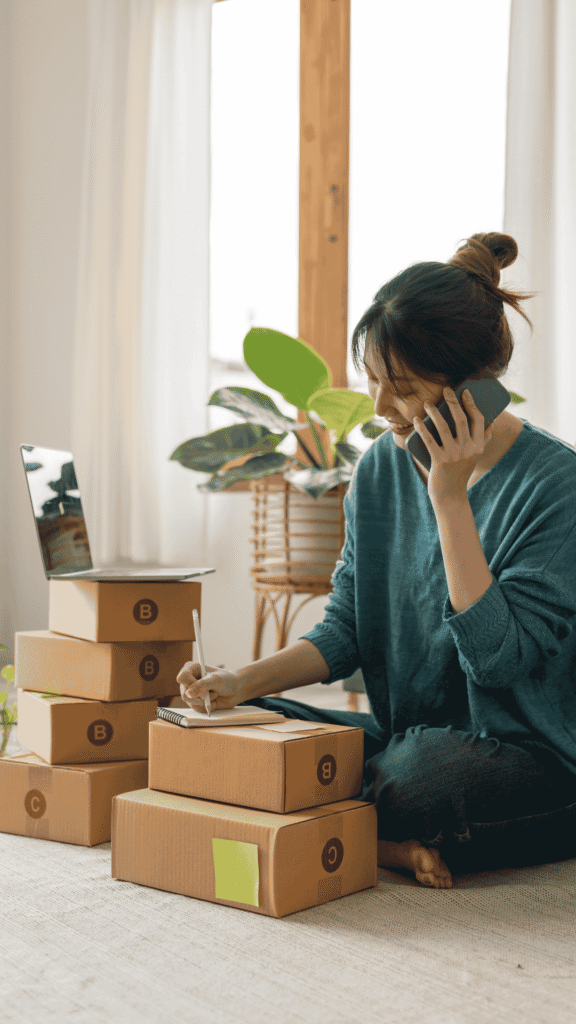 mujer sentada en el piso con cajas a un lado hablando por telefono