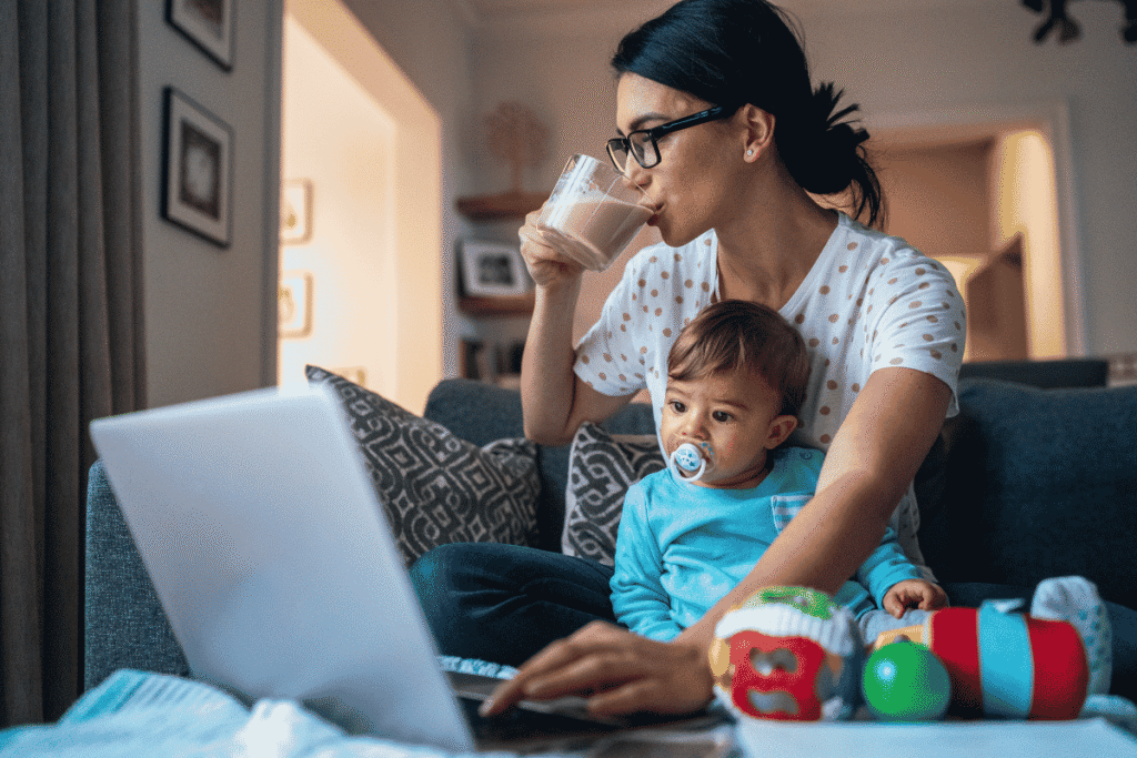 madre trabajando con su bebe en brazos tomando cafe